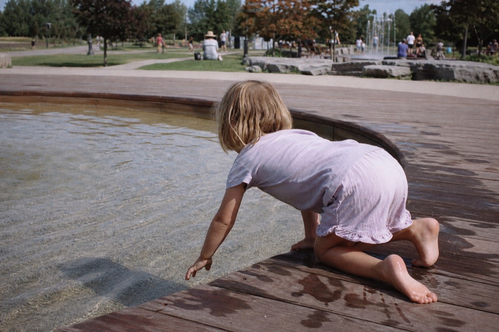 A child touching the glass of a shallow interactive pool, no text, no logos, no people