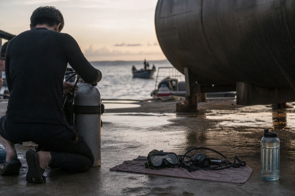Diver preparing scuba equipment beside a large aquarium tank, no text, no logos, no people