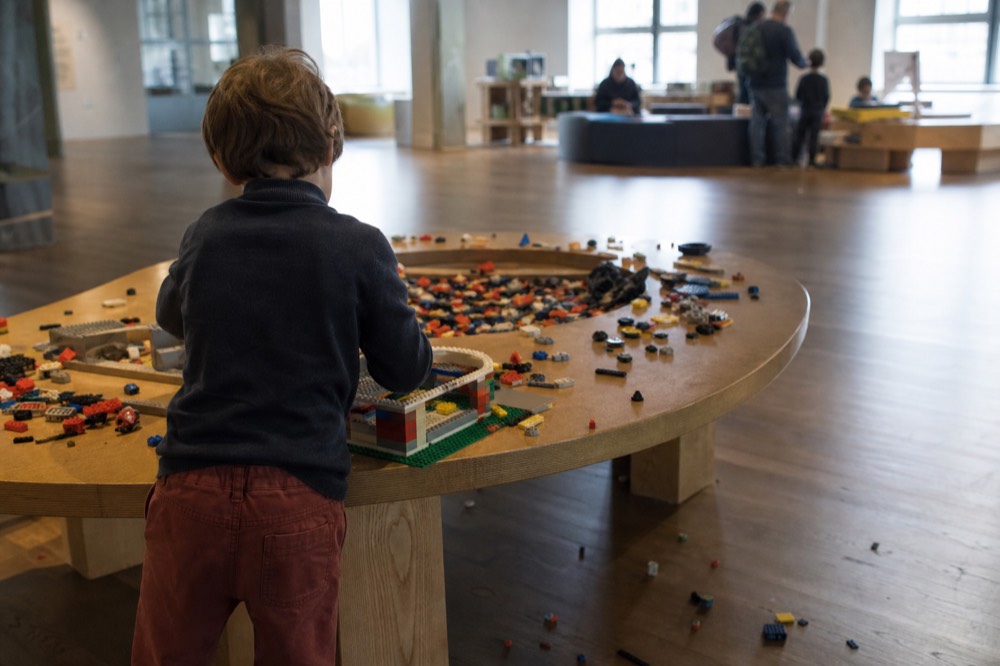 A bright interactive science exhibit hall with hands-on stations, no text, no logos, no people
