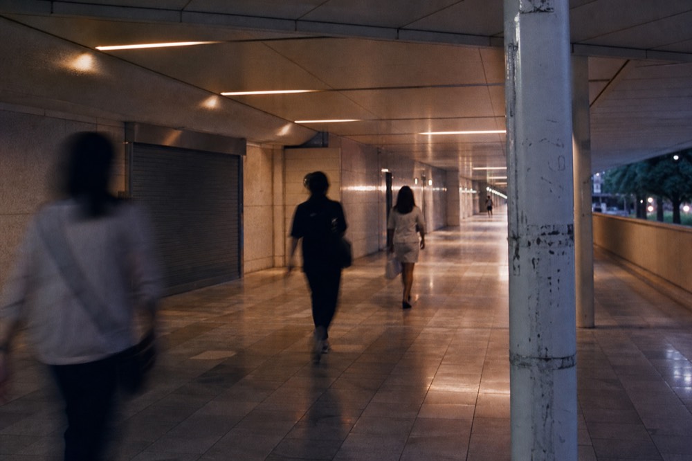 A covered walkway between glass towers in the KLCC precinct at dusk, no text, no logos, no people