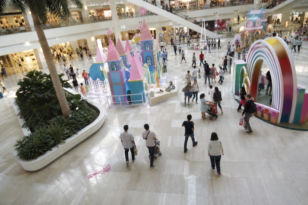 Crowded modern mall atrium with colorful display installations, no text, no logos, no people